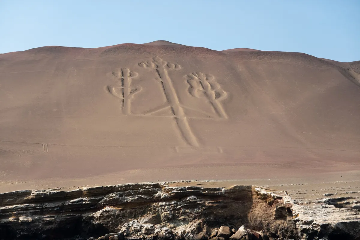 The Paracas Candelabra geoglyph carved into the peninsula hillside, seen from a Ballestas Islands tour boat, Peru