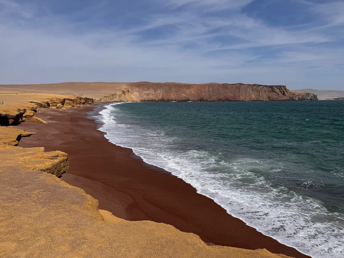 The red sand of Playa Roja against the ocean in the Paracas National Reserve on a Ballestas Islands tour, Peru